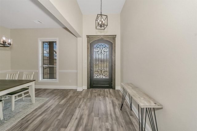 foyer entrance featuring an inviting chandelier, wood finished floors, baseboards, and a wealth of natural light