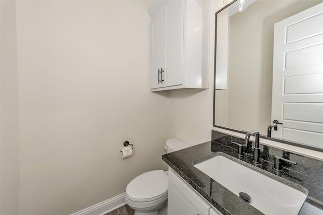 bathroom featuring vanity, toilet, wood finished floors, and baseboards