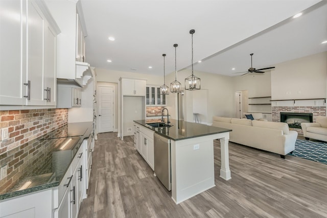 kitchen with a sink, dark countertops, stainless steel dishwasher, and ceiling fan