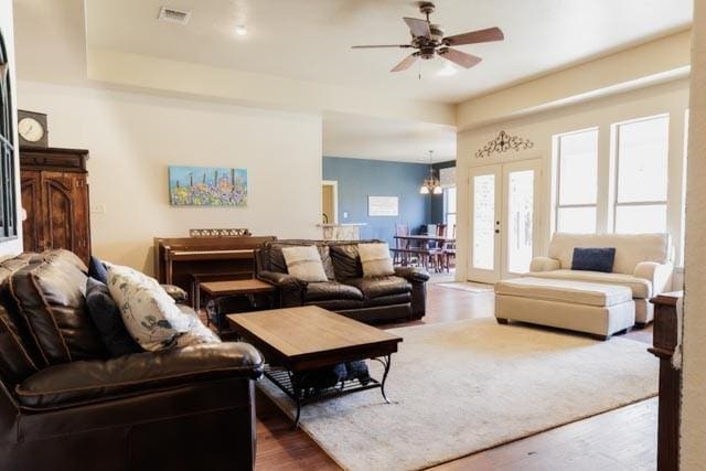 505 Spring Valley Rd, Paradise, TX 76073 - living room with french doors, wood finished floors, visible vents, and ceiling fan with notable chandelier