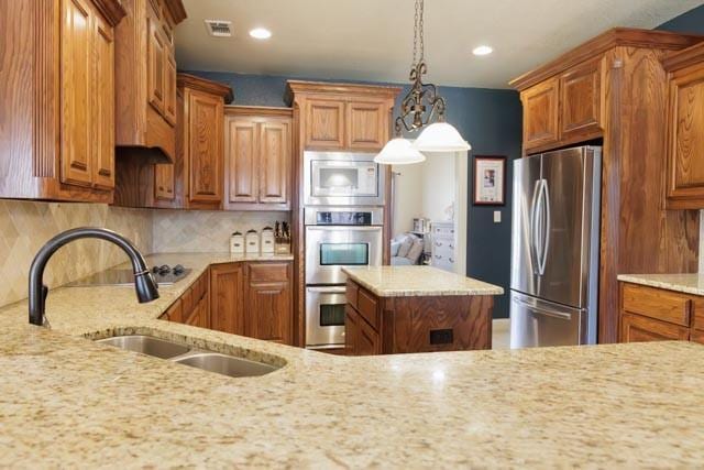 505 Spring Valley Rd, Paradise, TX 76073 - kitchen with a sink, visible vents, light stone countertops, brown cabinetry, and appliances with stainless steel finishes