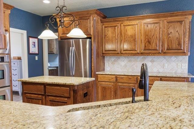 505 Spring Valley Rd, Paradise, TX 76073 - kitchen featuring brown cabinetry, tasteful backsplash, and stainless steel appliances