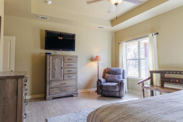 505 Spring Valley Rd, Paradise, TX 76073 - bedroom featuring a tray ceiling, wood finished floors, visible vents, and baseboards