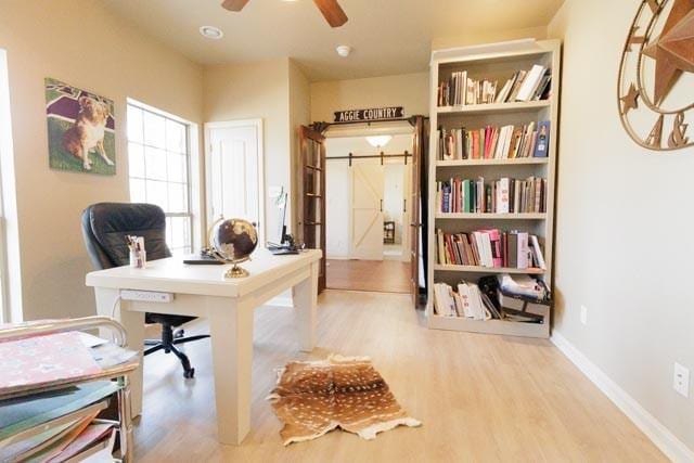 505 Spring Valley Rd, Paradise, TX 76073 - home office featuring baseboards, wood finished floors, ceiling fan, and a barn door
