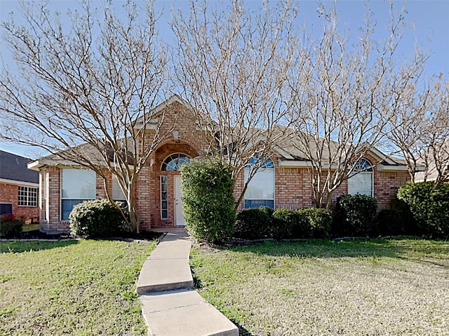 single story home featuring a front yard and brick siding