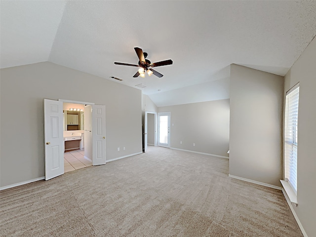 empty room with lofted ceiling, light colored carpet, visible vents, and ceiling fan