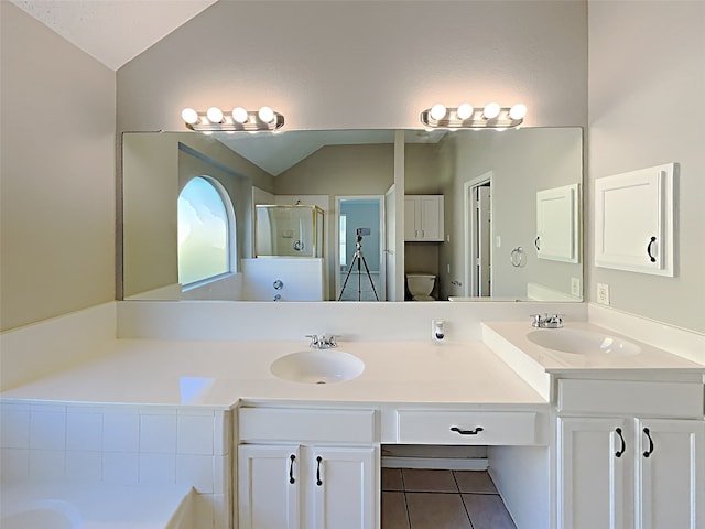 bathroom with vaulted ceiling, tile patterned floors, a shower stall, and a sink