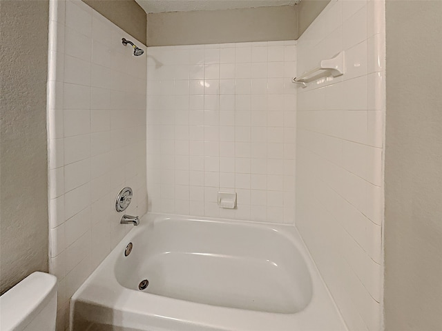 bathroom with a textured ceiling, shower / bath combination, toilet, and a textured wall