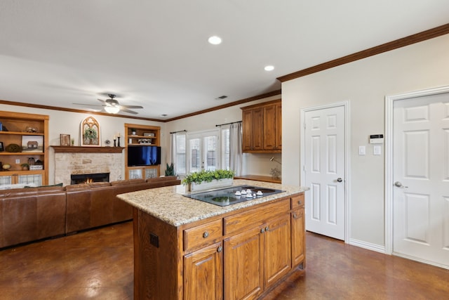 kitchen featuring a center island, finished concrete flooring, a stone fireplace, a ceiling fan, and black electric cooktop