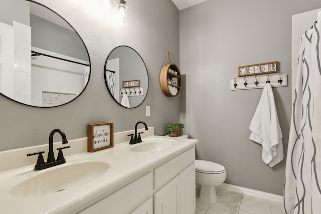 bathroom with double vanity, toilet, baseboards, and a sink