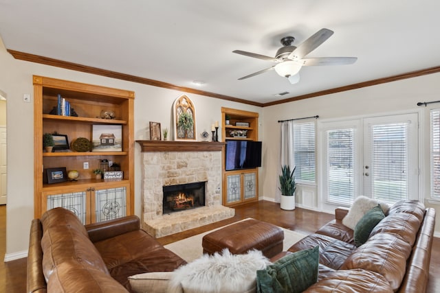 living room featuring visible vents, built in shelves, ornamental molding, a ceiling fan, and dark wood-style flooring