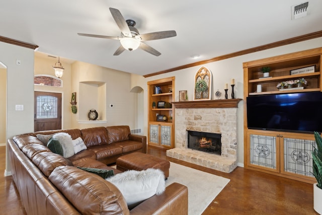 living room with built in shelves, a ceiling fan, visible vents, a fireplace, and arched walkways