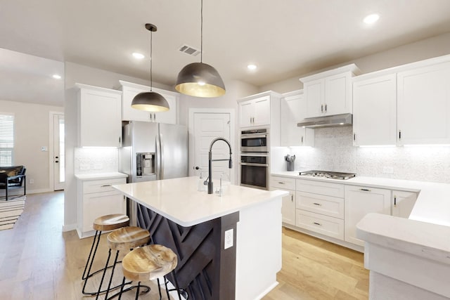 529 Hummingbird Dr, Celina, TX 75009 - kitchen with decorative backsplash, light wood-type flooring, stainless steel appliances, under cabinet range hood, and visible vents