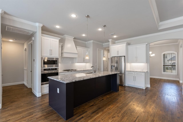 kitchen featuring an island with sink, dark wood-style floors, appliances with stainless steel finishes, custom exhaust hood, and a sink