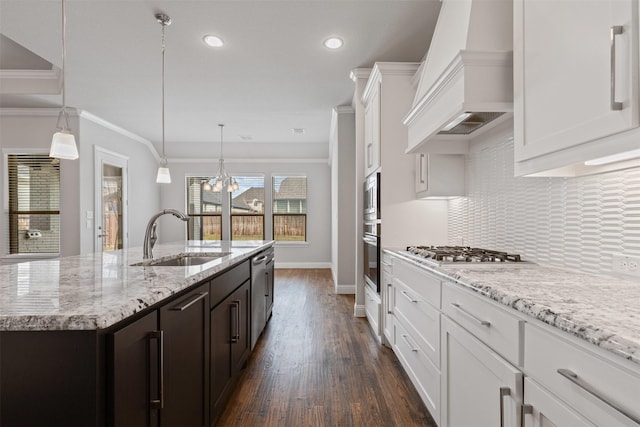 kitchen featuring tasteful backsplash, premium range hood, appliances with stainless steel finishes, white cabinetry, and a sink