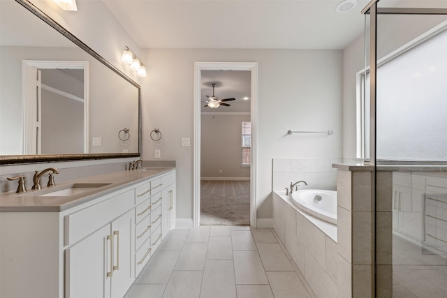 full bath featuring ceiling fan, a garden tub, double vanity, and a sink