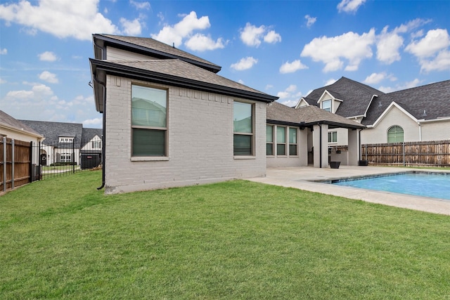 rear view of house with a patio, a fenced in pool, a yard, a fenced backyard, and brick siding