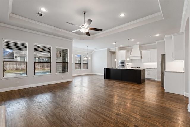 unfurnished living room with dark wood-style floors, ceiling fan, a tray ceiling, and ornamental molding