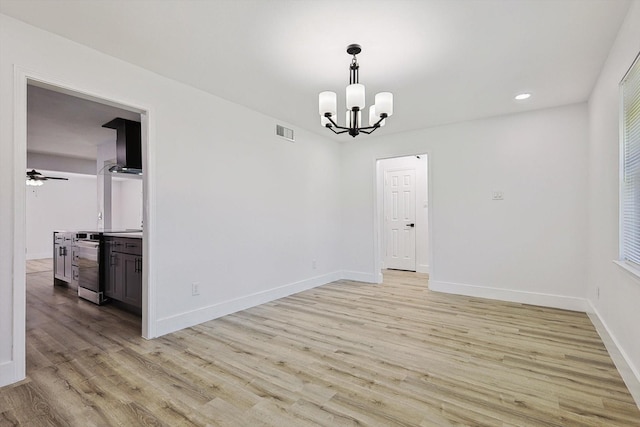 unfurnished dining area with visible vents, baseboards, recessed lighting, light wood-style flooring, and ceiling fan with notable chandelier