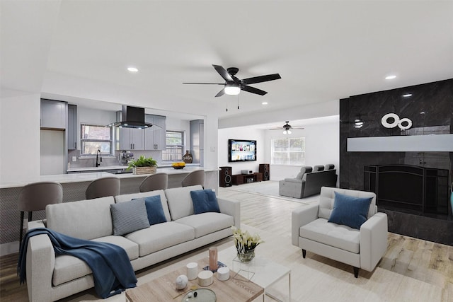 living room with a ceiling fan, recessed lighting, a fireplace, and light wood finished floors