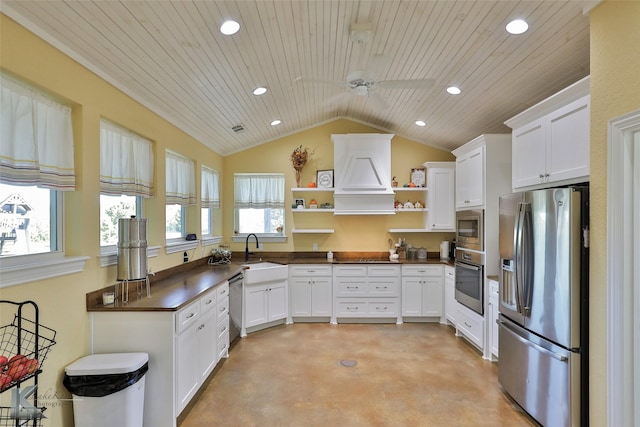 kitchen with open shelves, a sink, dark countertops, appliances with stainless steel finishes, and concrete flooring