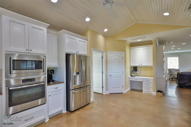 kitchen with vaulted ceiling, white cabinets, appliances with stainless steel finishes, and finished concrete floors