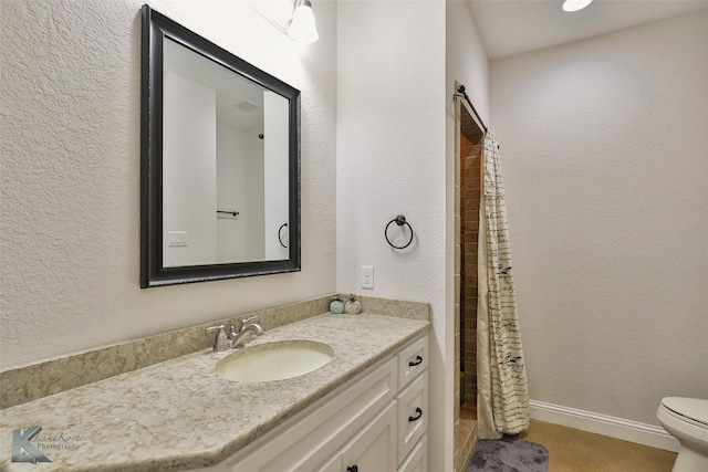 full bath featuring vanity, a shower with shower curtain, baseboards, toilet, and a textured wall