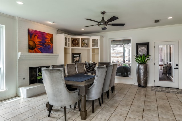 dining room with visible vents, ornamental molding, a fireplace, light tile patterned floors, and ceiling fan