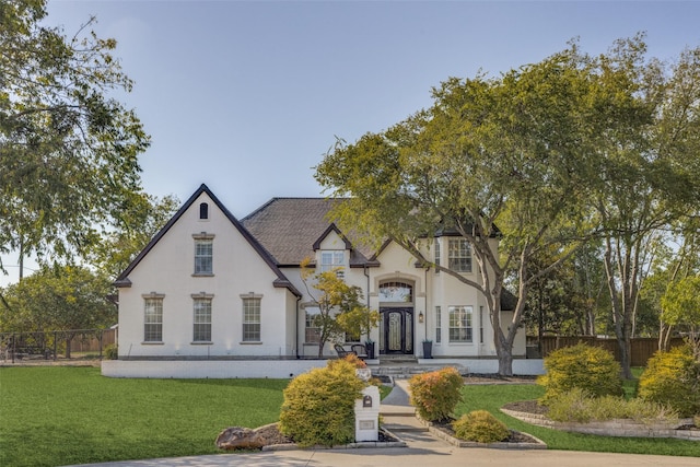 view of front of house with a front yard, fence, and stucco siding