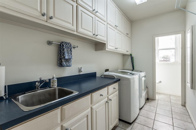 washroom with a sink, baseboards, light tile patterned flooring, cabinet space, and separate washer and dryer