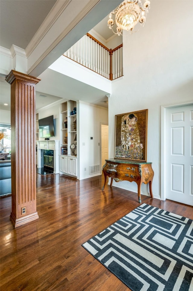 foyer with visible vents, wood finished floors, crown molding, and decorative columns