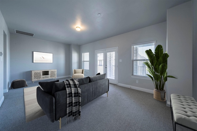 living area featuring baseboards, visible vents, and light carpet