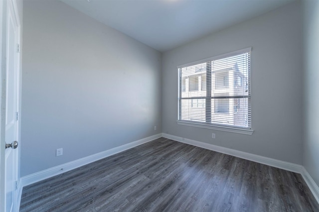 unfurnished room with dark wood-style flooring and baseboards