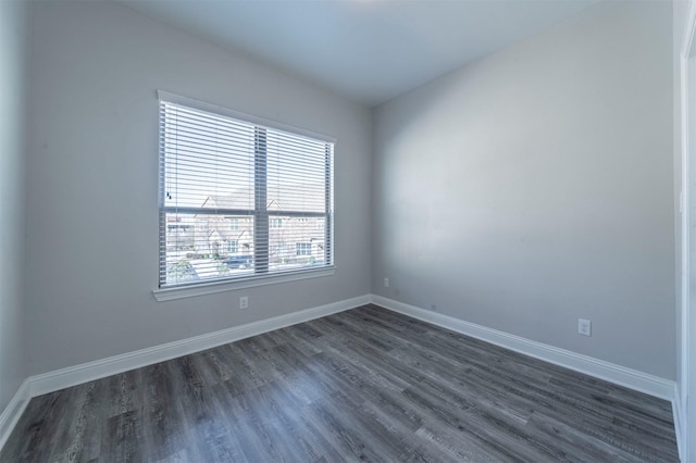 unfurnished room with baseboards and dark wood-type flooring