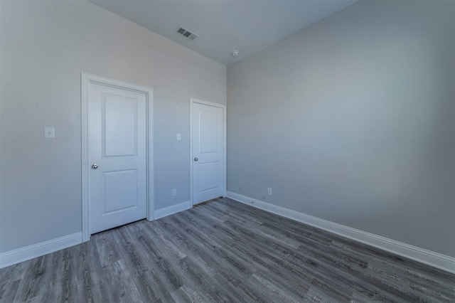 unfurnished room with baseboards, visible vents, and wood finished floors