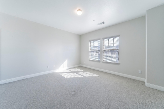 spare room featuring baseboards, light carpet, and visible vents