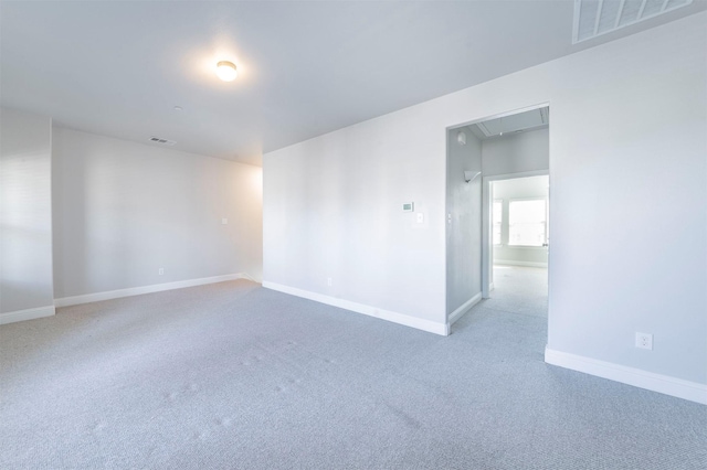 carpeted empty room with baseboards, attic access, and visible vents