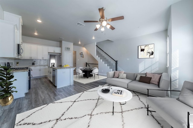living area featuring visible vents, stairs, recessed lighting, a ceiling fan, and dark wood finished floors