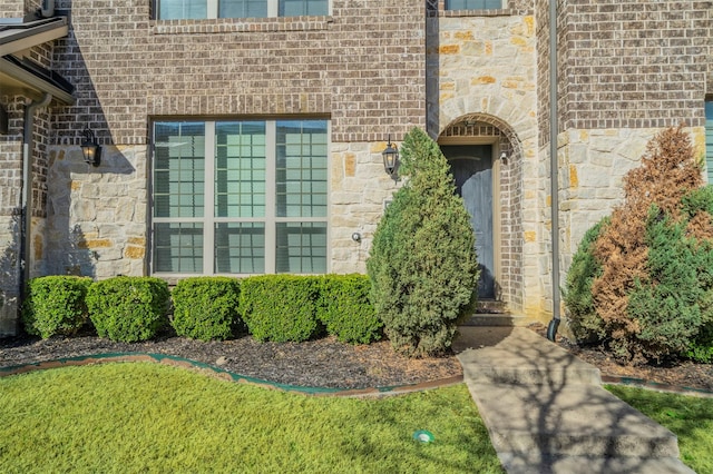view of exterior entry with brick siding and stone siding