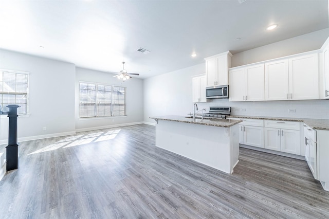 kitchen featuring visible vents, appliances with stainless steel finishes, light stone counters, and light wood-type flooring