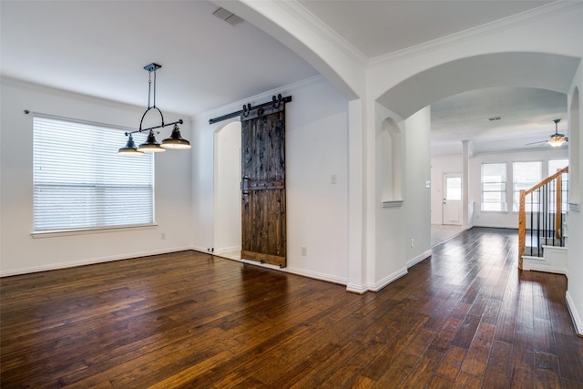 spare room featuring visible vents, a barn door, dark wood-style floors, and a ceiling fan