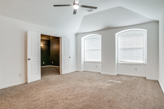 empty room featuring visible vents, light colored carpet, lofted ceiling, and ceiling fan