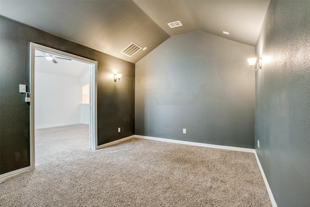 carpeted spare room with lofted ceiling, baseboards, visible vents, and ceiling fan