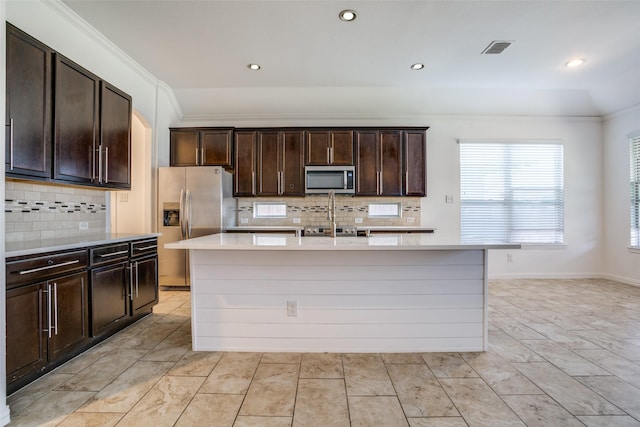 kitchen featuring visible vents, an island with sink, ornamental molding, stainless steel appliances, and light countertops