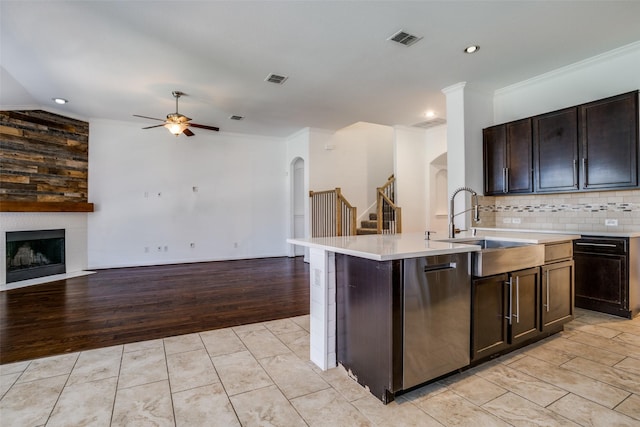 kitchen with stainless steel dishwasher, open floor plan, arched walkways, and a sink