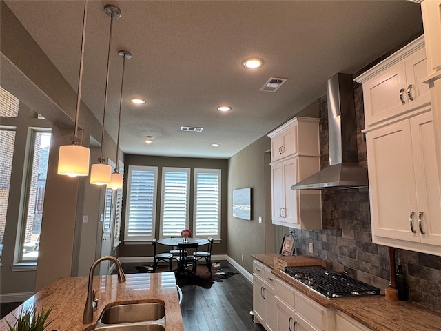 kitchen featuring a sink, visible vents, stainless steel gas stovetop, and wall chimney exhaust hood