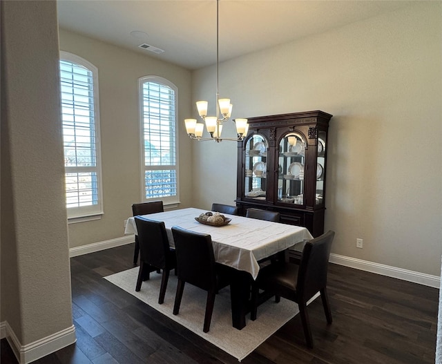 dining room featuring dark wood finished floors, a notable chandelier, visible vents, and baseboards