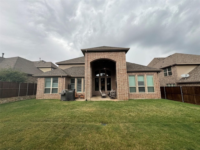 back of property with a yard, brick siding, and a fenced backyard