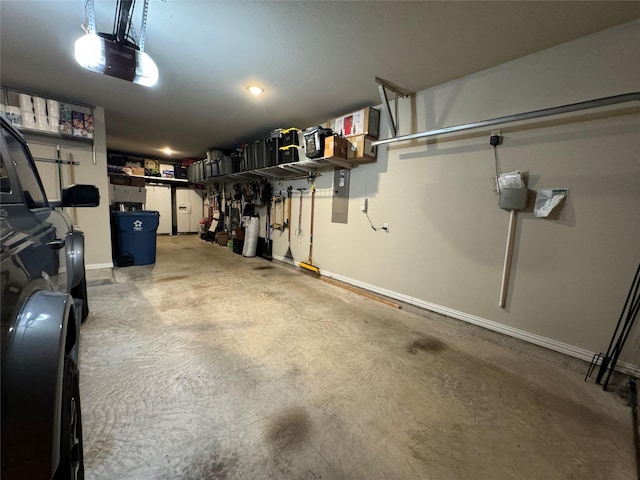 garage featuring electric panel, baseboards, and a garage door opener