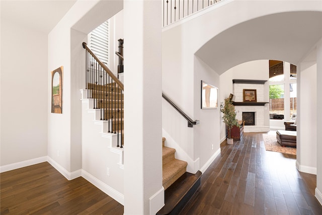 interior space with arched walkways, a glass covered fireplace, hardwood / wood-style floors, and baseboards